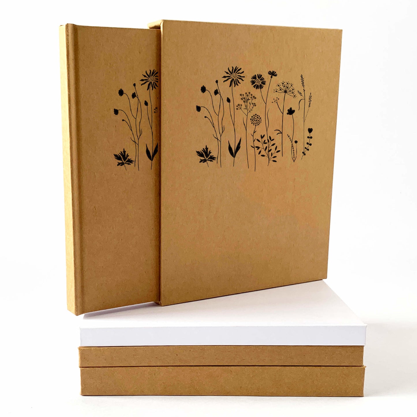 Hardback book slipcase to house and protect custom handbound journals and notebooks, standing on a stack of handmade journals in kraft and white.