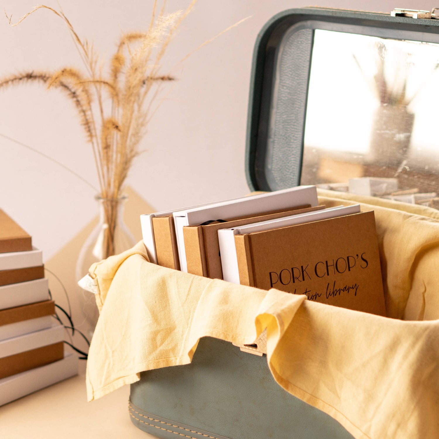 Custom hand-bound journals & notebooks displayed in a vintage trunk, showcasing unique designs and quality craftsmanship.