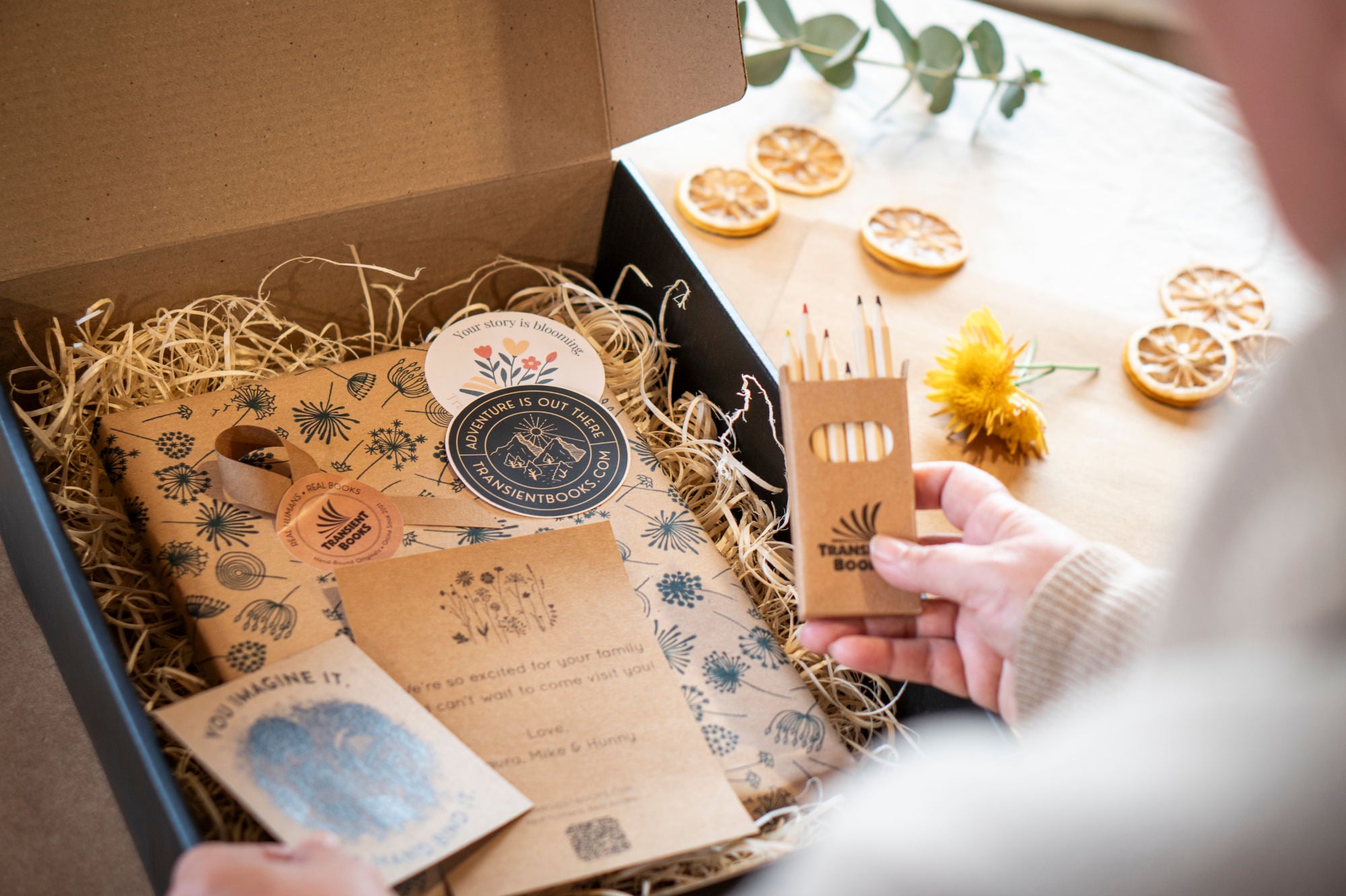 Unboxing of a product with decorative elements and a hand holding a small box.