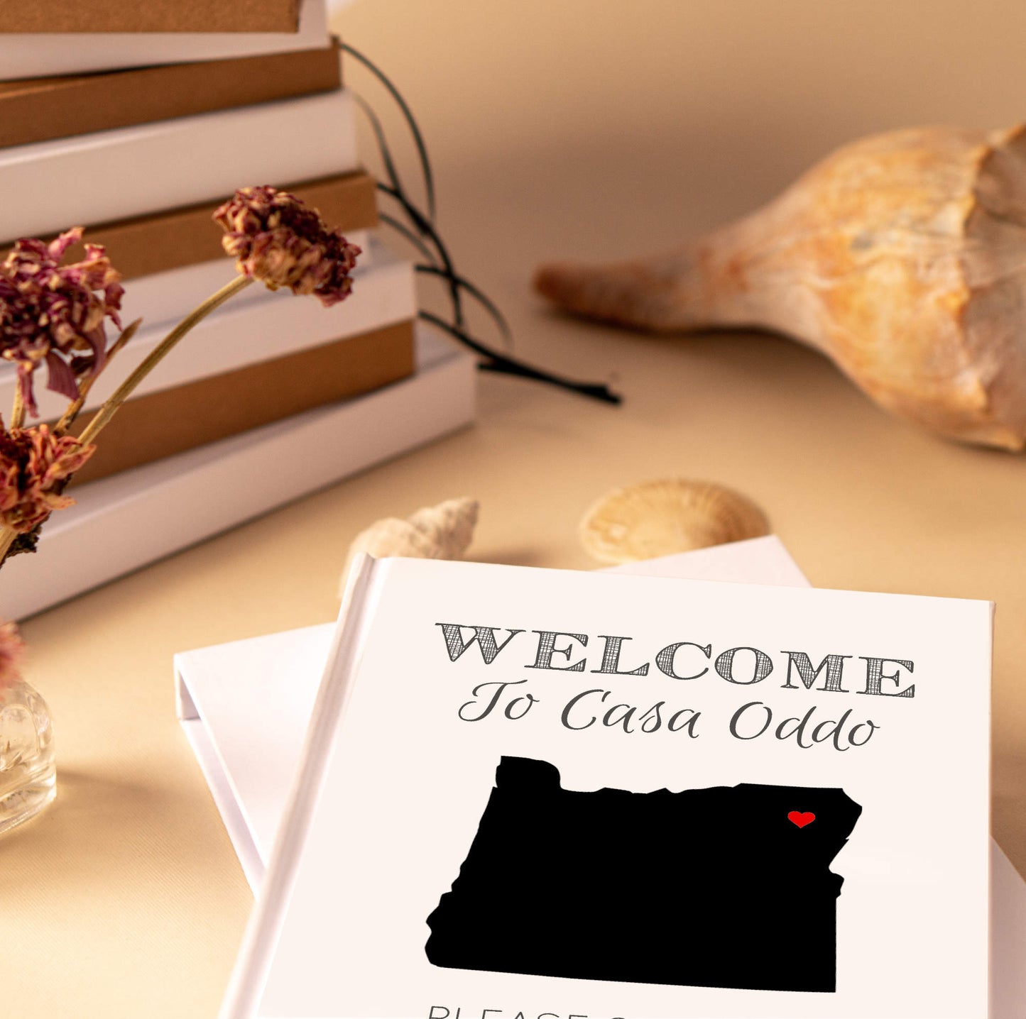Personalized home guest book with custom state map on the cover highlighting the homes location. Book is on an entry way table, waiting for guests.