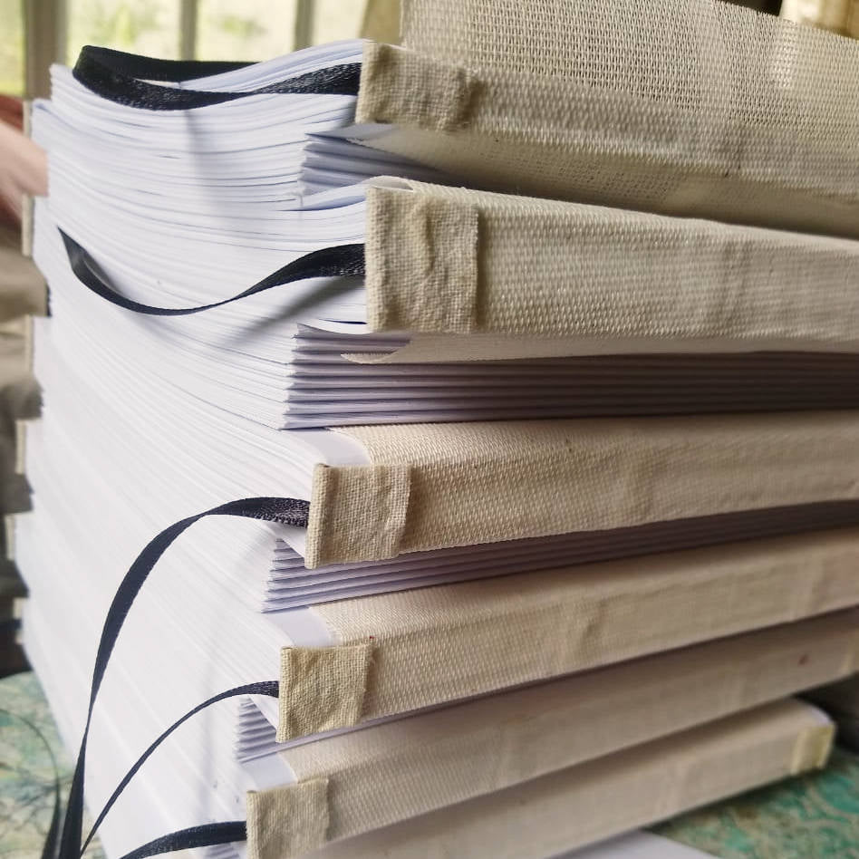 A stack of hand-sewn custom handbound books, showcasing reinforced spines for added durability.