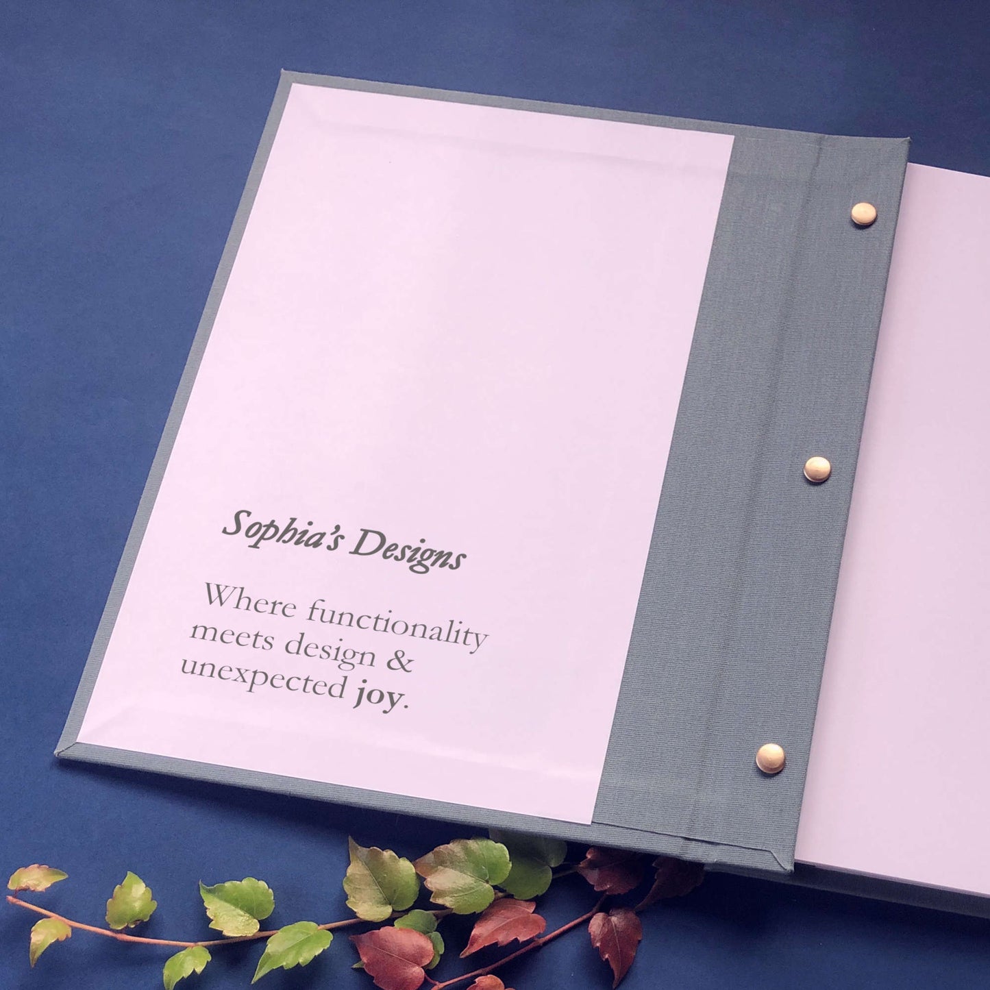 Personalized presentation portfolio with brass screw posts open on a decorated table with personalized text printed on the inside front cover.