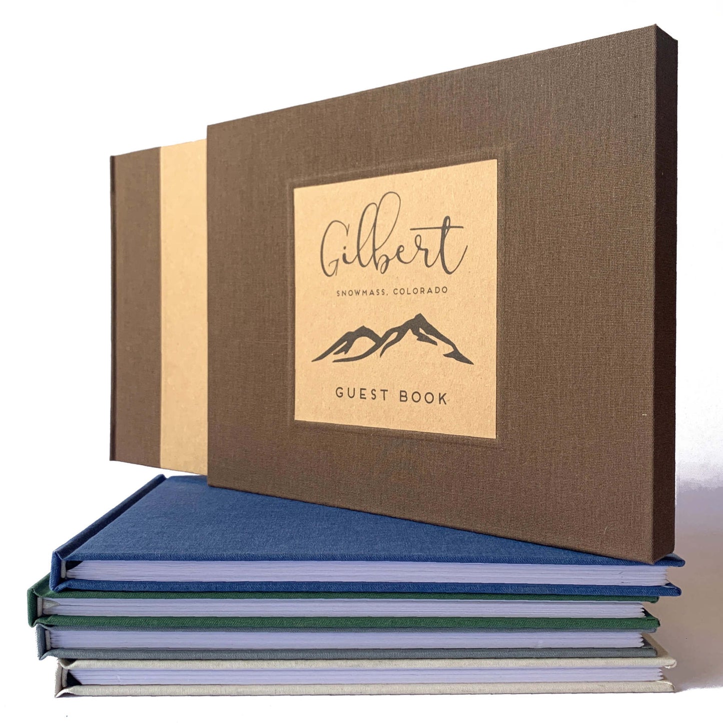Rustic brown linen canvas on a book slip case handcrafted to house a personalized guest book, standing on a stack of custom made guest books.