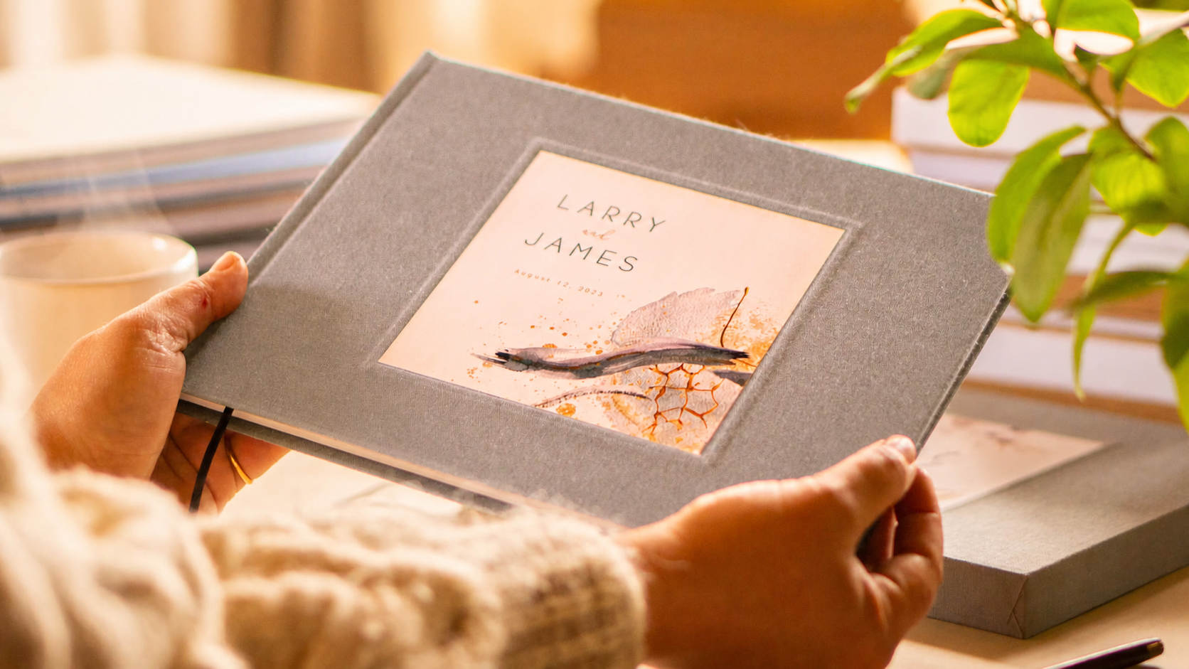 Gray linen wedding guest book, handheld in front of a wedding guest book table.