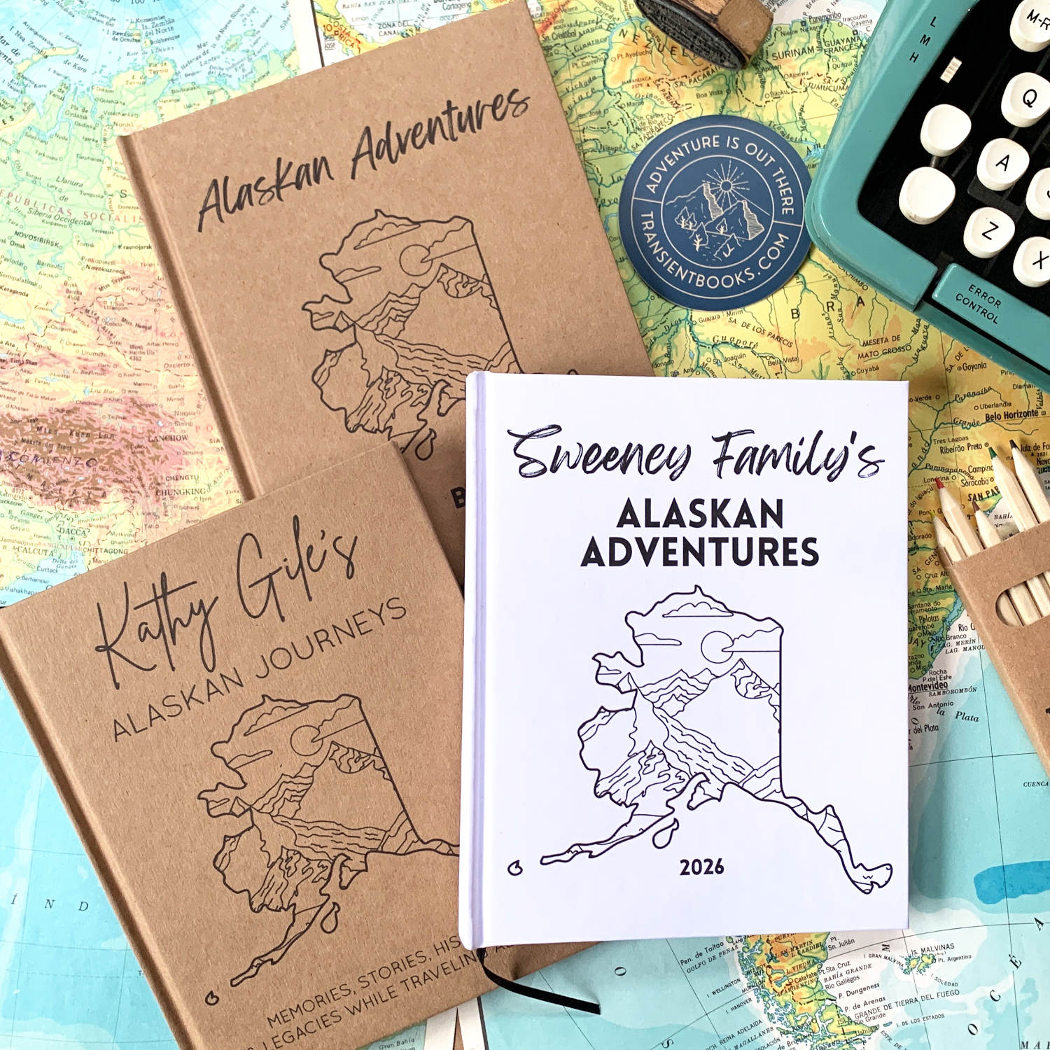 Three travel journals with Alaska-themed covers on a map background