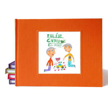 Bright orange birthday party guest book idea with personalized illustration on the cover drawn by a kid. The drawing is of 2 kids playing with cars and it says "Feliz Cumple Elias!!"