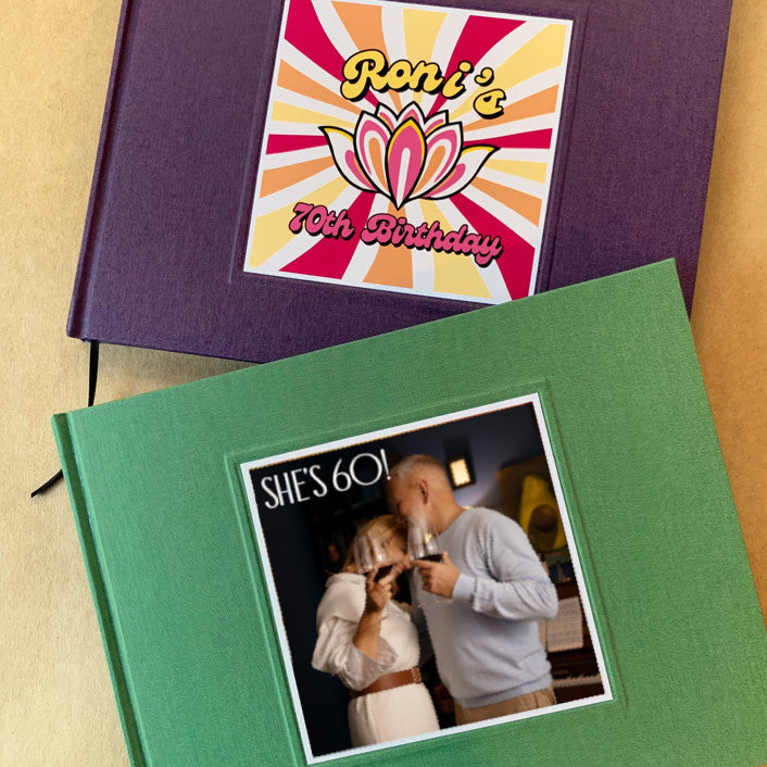 Two birthday party guest books on a table, one green, one purple, with customized covers with photos and birthday logos. Hardback, made to order, heirloom quality.