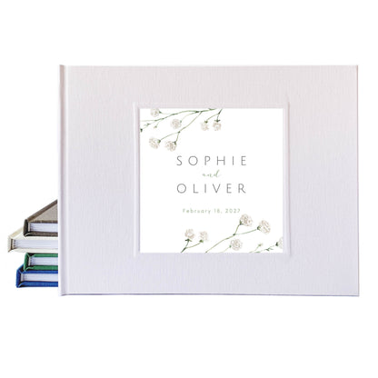 White linen wedding guest book with botanical cover art, personalized with bride and groom's names and their wedding date.