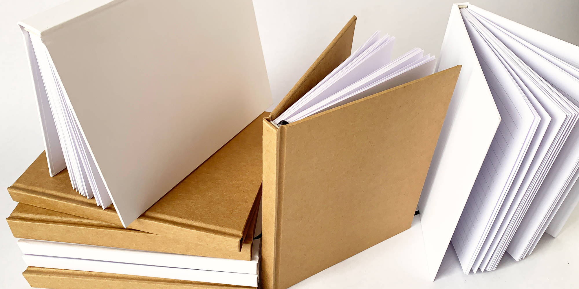 Set of bulk journals on a table top in a variety of positions. Open, closed, standing, lined pages visible.