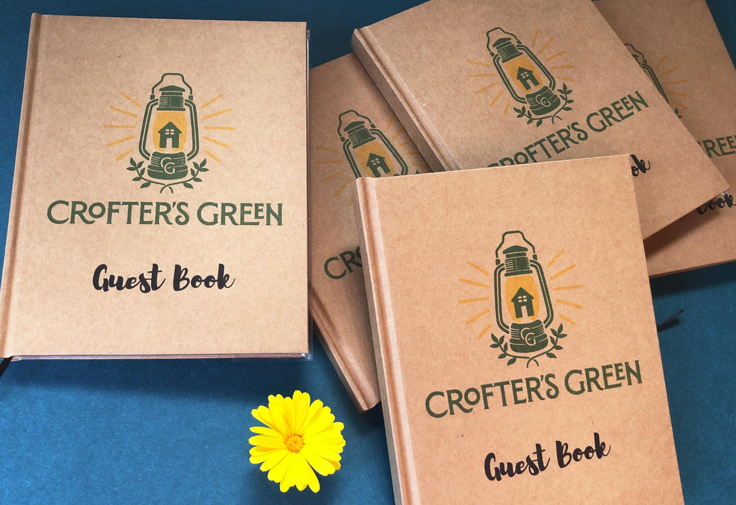 Personalized Crofter's Green guest books on a blue background with a yellow flower.