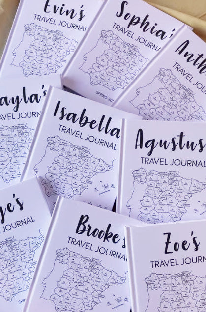 Collection of personalized travel journals with names printed on them and travel maps of spain on the front.