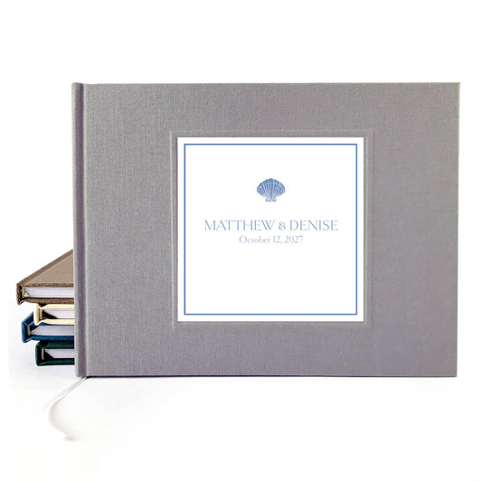 Gray linen hardback wedding guest book with custom names and wedding date on the cover. Seashell artwork incorporated.