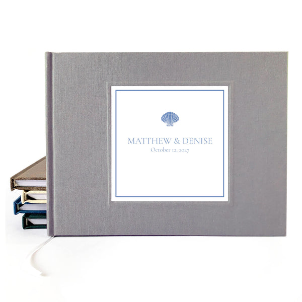 Gray linen hardback wedding guest book with custom names and wedding date on the cover. Seashell artwork incorporated.