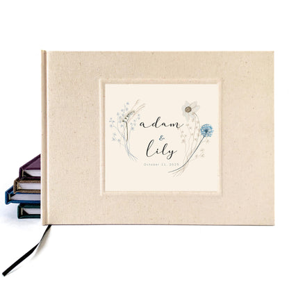 Cream linen wedding guest book for outdoor, natural boho commitment ceremony. Personalized wildflower bouquet design on cover with names and wedding date. 