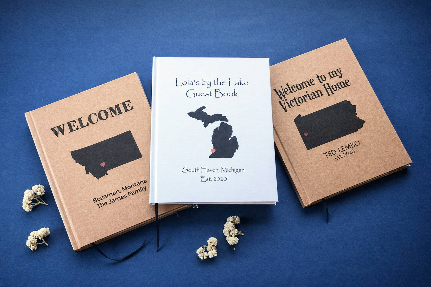 Three personalized house guest books with state illustrations and custom text on a blue background. Books are custom made, hardback.
