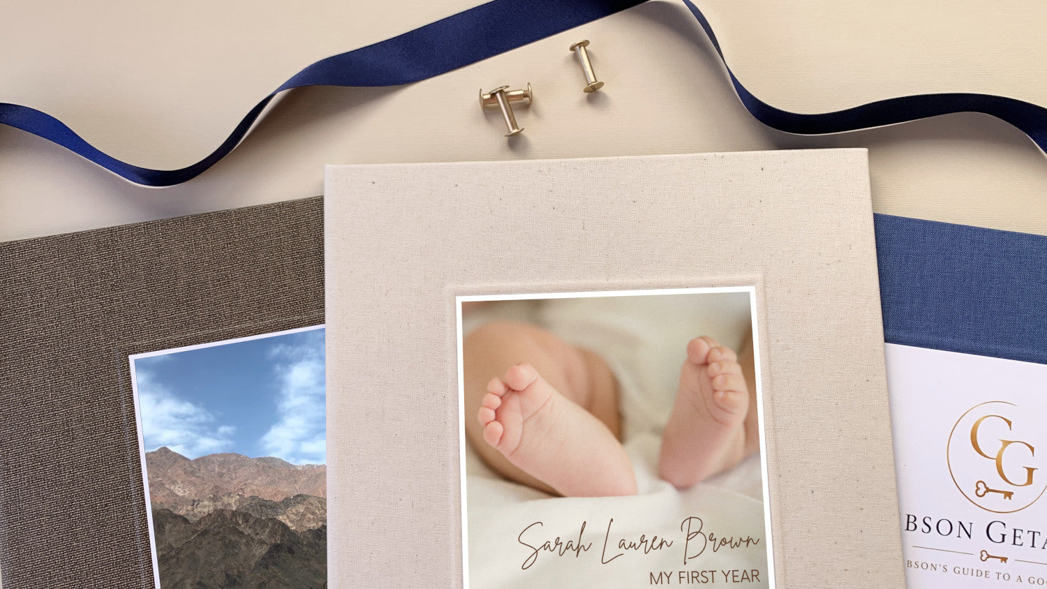 Three linen covered scrapbooks in brown, cream and navy blue on a table with brass screwposts and ribbon, each with it's own personalized cover inlay.
