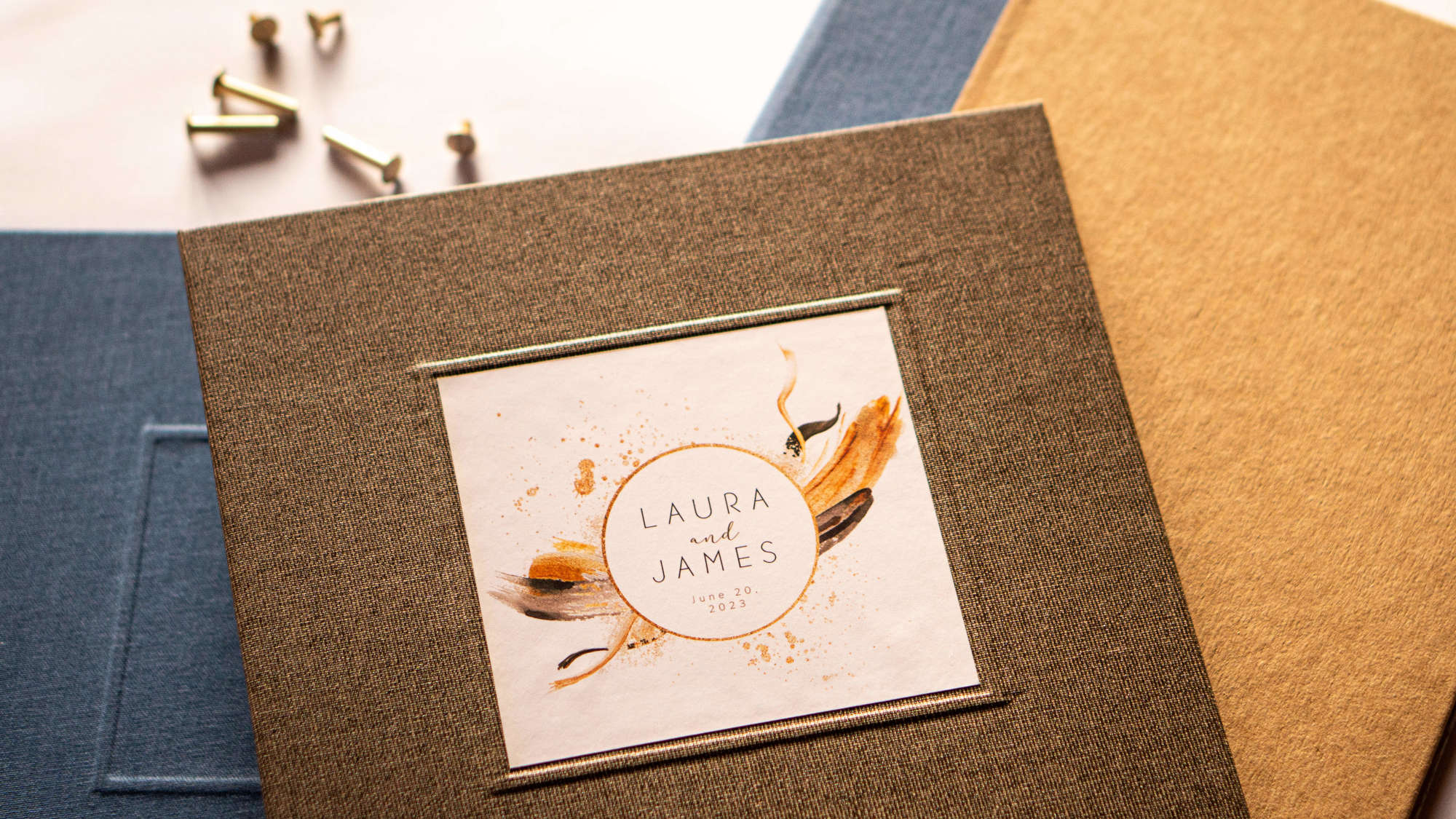 Handbound custom scrapbook albums with linen fabric covers on a table top with brass screwposts. 