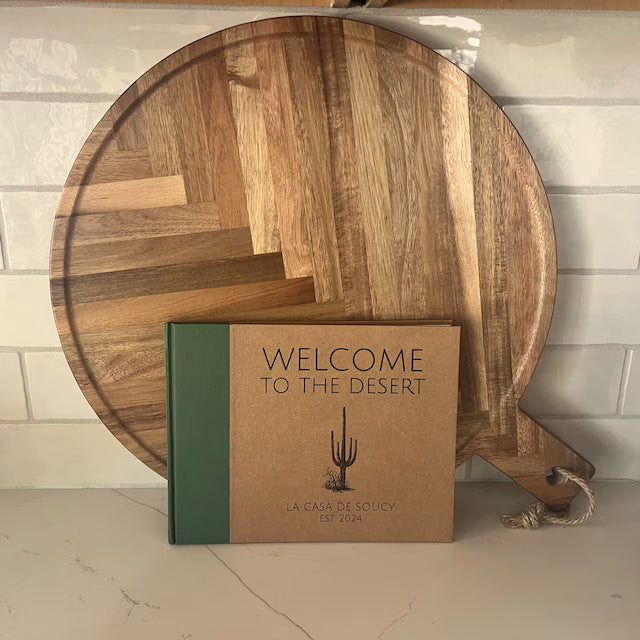 Personalized guest book for desert home on a kitchen counter. Modern hard back design with cactus art and custom text on the cover. Forest green and kraft cover colors.