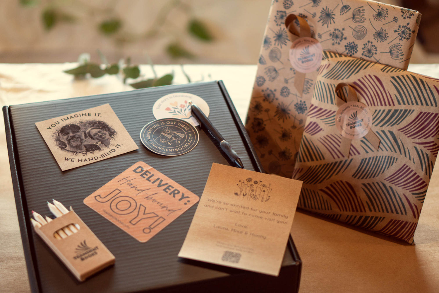 Gift box for personalized gift books that are gift wrapped. Gift Box components on top of box: pen, postcard, pencils, gift note, vinyl stickers, colored pencils.