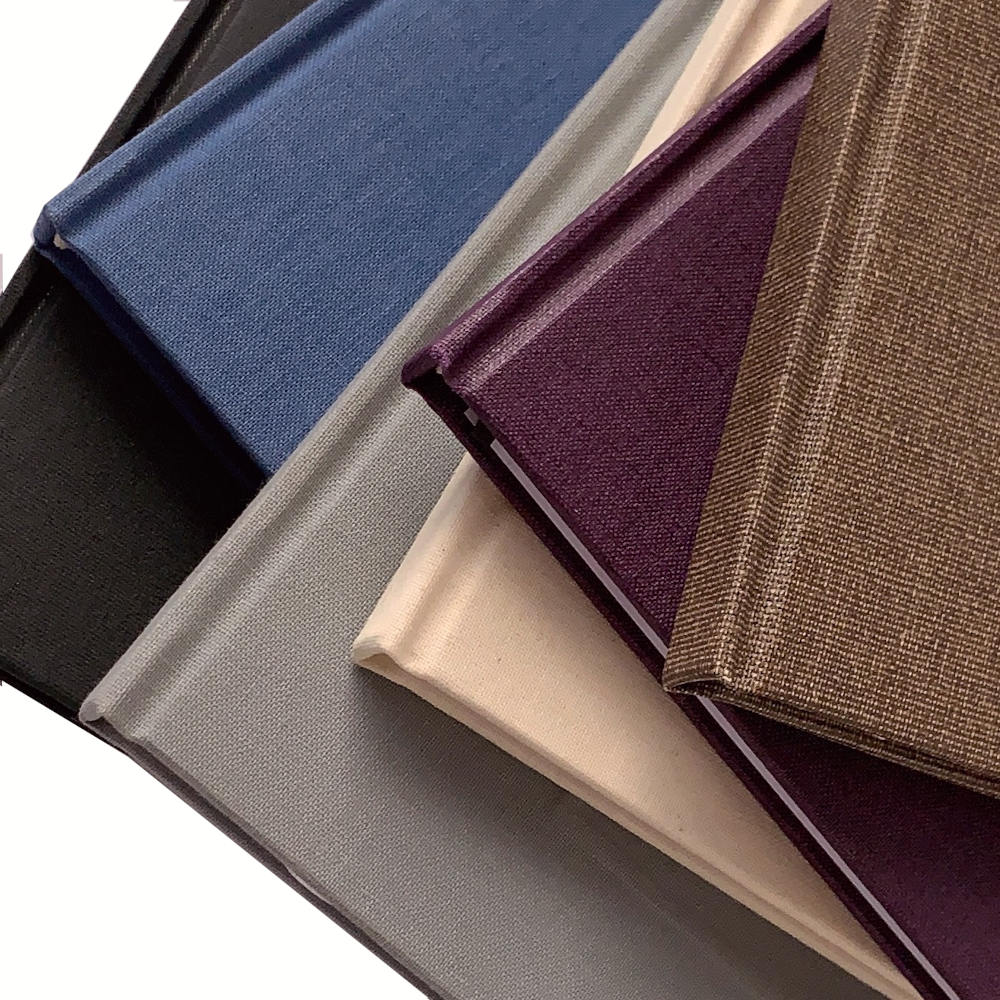 Collection of hand bound books showing texture of binding canvas used in a variety of colors.