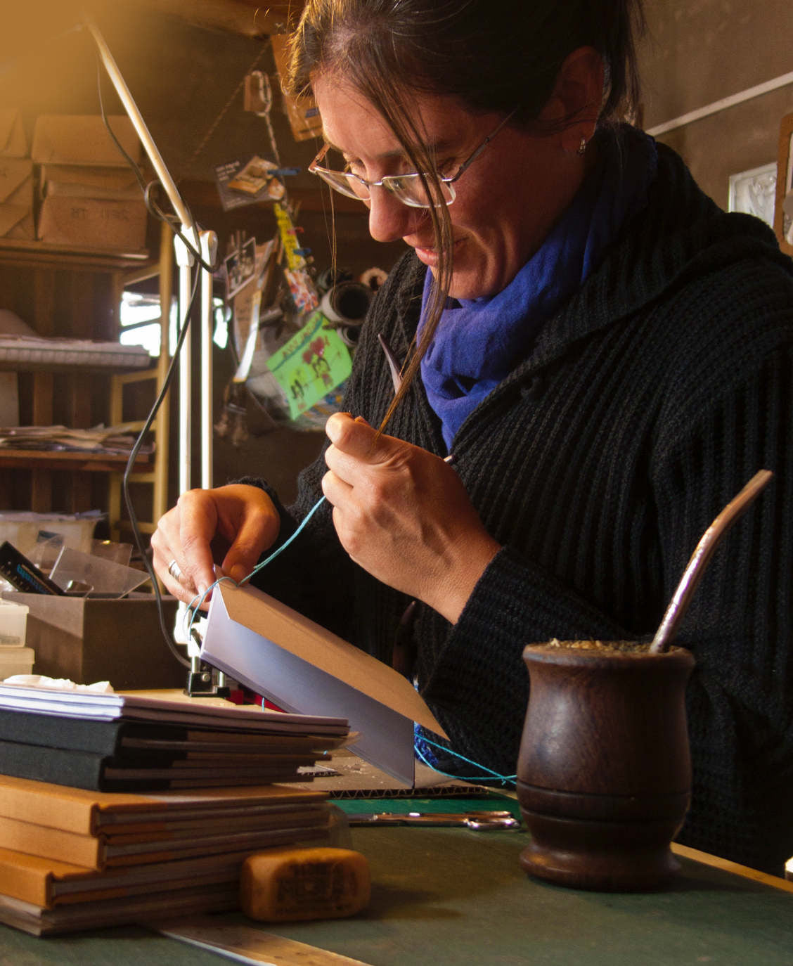 Alex hand sewing a stack of custom books in the Transient Books bindery. 