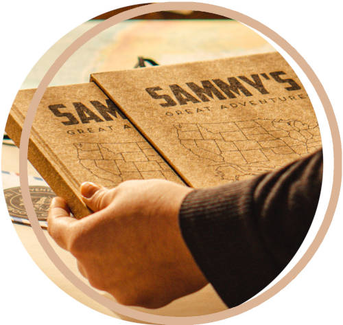 Hand holding a handbound book in book slipcase labeled 'Sammy's Great Adventure' with a custom map design.