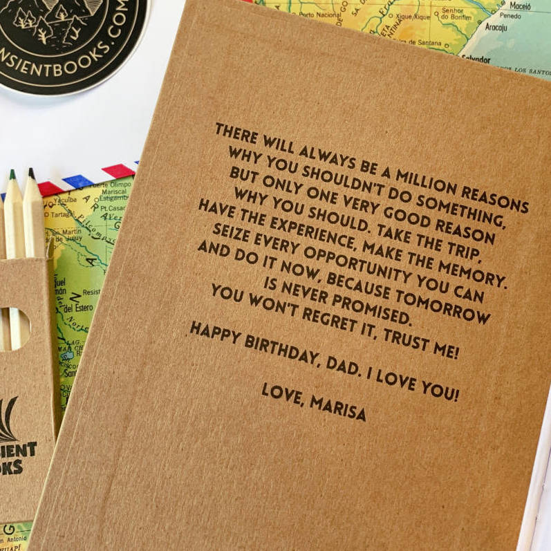 personalized travel notebook with a motivational quote on the inside front cover, laying on a table with a map