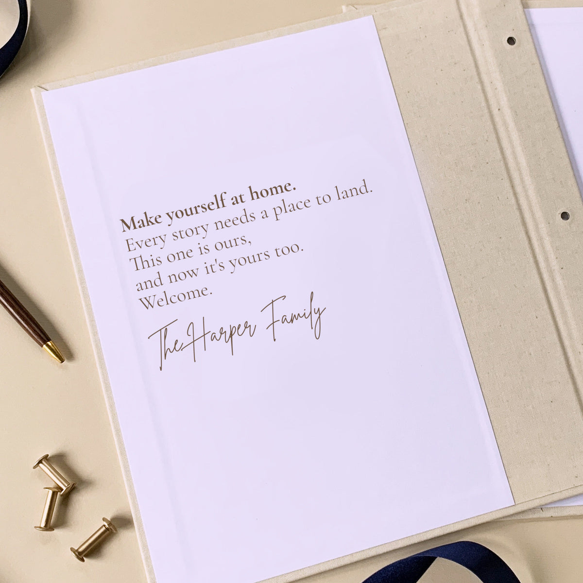 Custom printed inside front cover of a linen covered scrapbook album on a table next to a pen and brass screwposts.