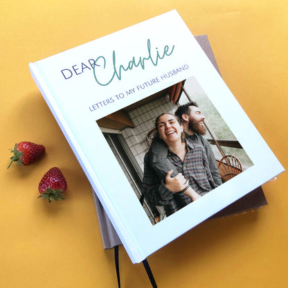 Personalized letters to my husband journal with custom photo and text on the cover. Hard back, hand bound book, heirloom quality. White cover on a yellow table with strawberries.