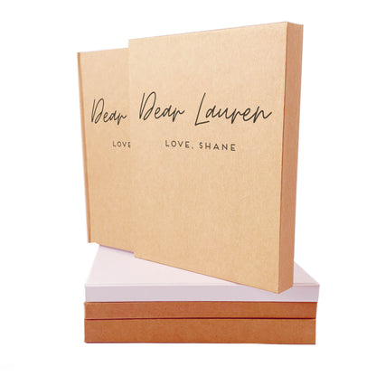 Letters to husband couple's journal with custom text on the front, poised on top of a stack of books, housed in a matching book slipcase.