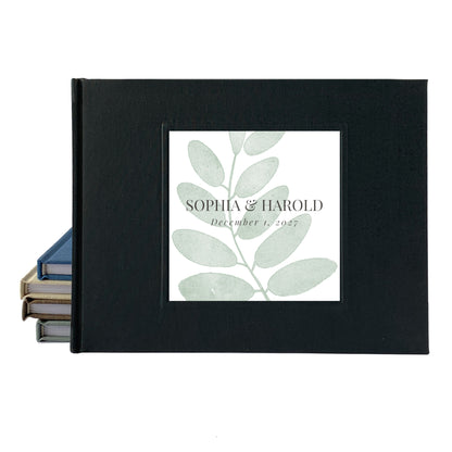Black linen outdoor wedding guest book with simple leaf personalized on the front with the couple's names and wedding date.