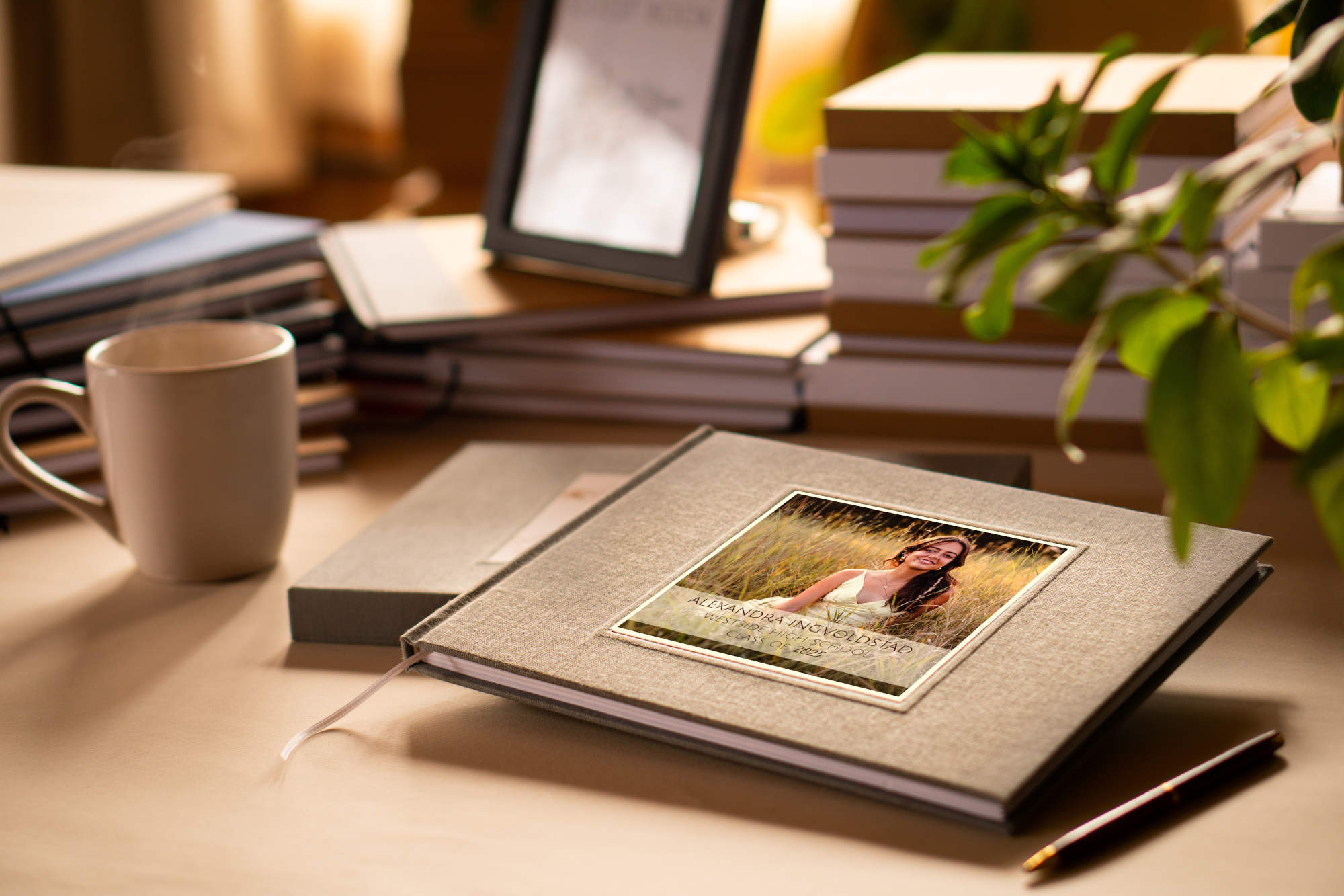Personalized graduation guest book with graduation photo on the cover on a table, ready for guests. Surrounded by other custom made heirloom quality books and a pen.