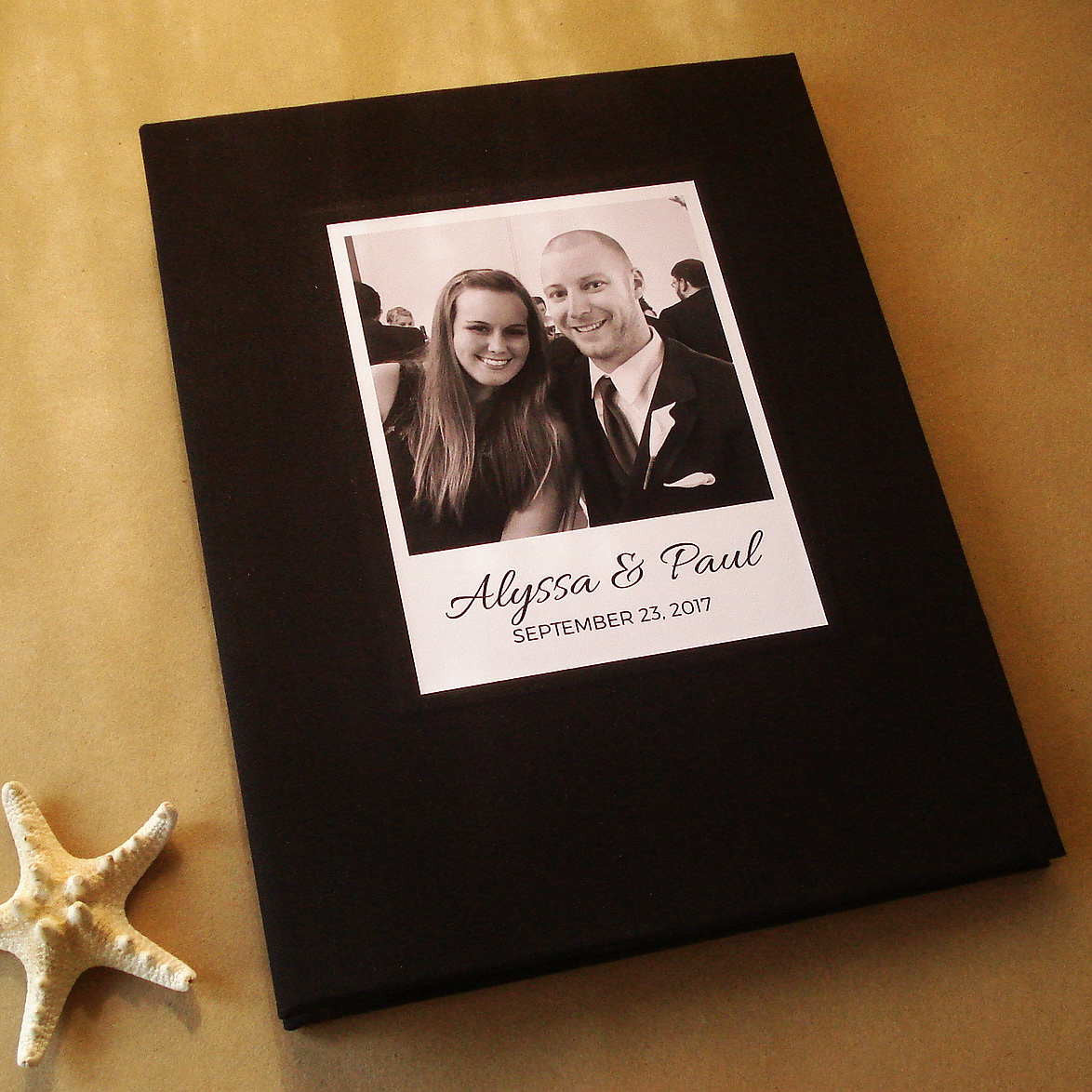 Personalized black photo guest book for a wedding with a cover featuring a couple's portrait and date on a beige surface. Custom made. Heirloom quality.