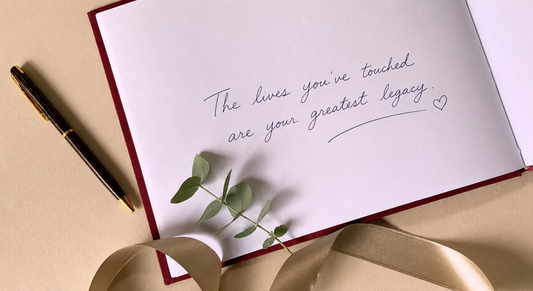 Retirement party guest book open on a table with a meaningful message handwritten on the page next to a pen and a ribbon.