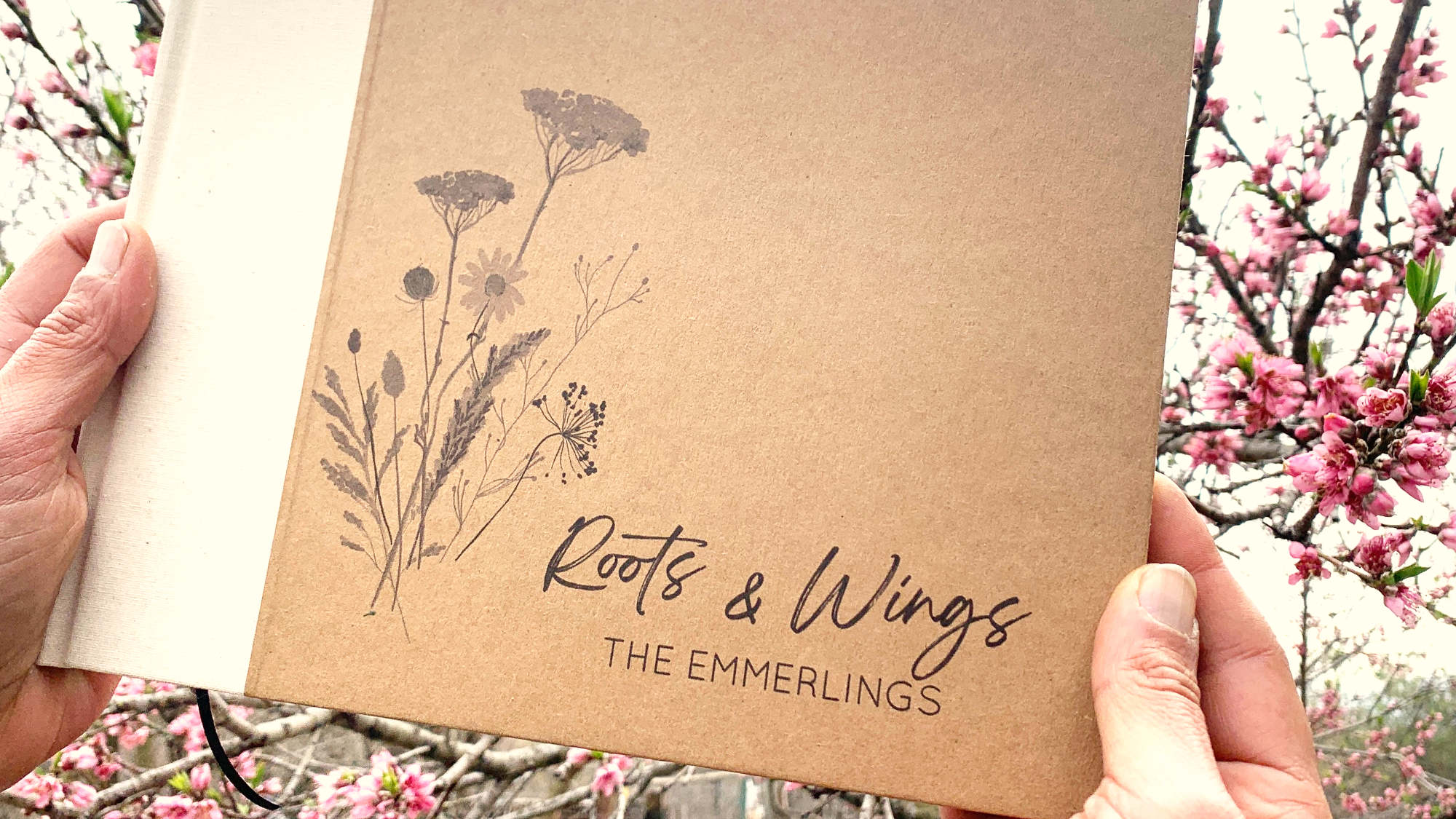 Retirement party guest book for signing farewell wishes. Wildflower design, custom text, handcrafted, heirloom quality. Held by hand in front of a flowering peach tree. 