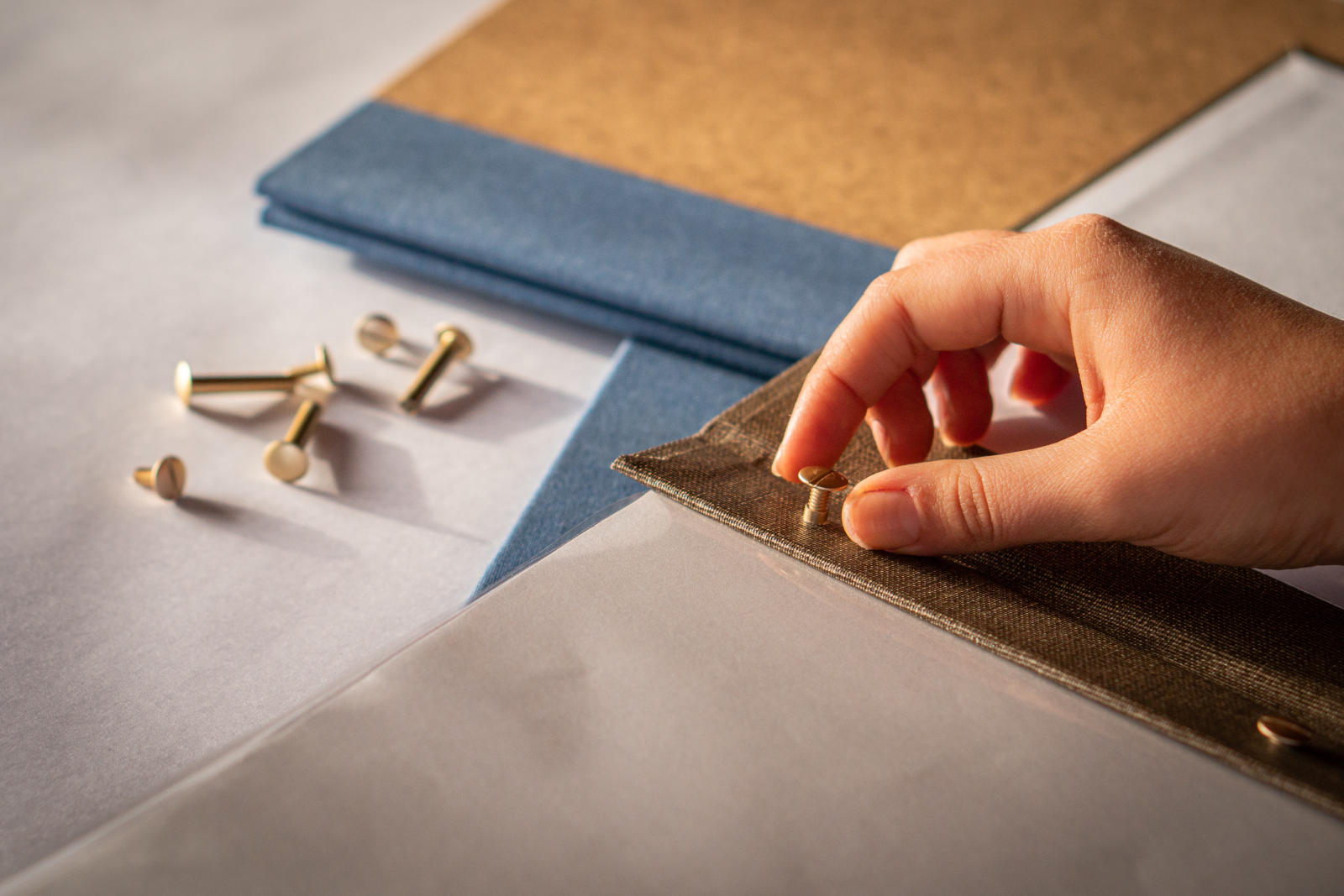 Close-up of a hand removing brass screw posts from a binder with removable pages.