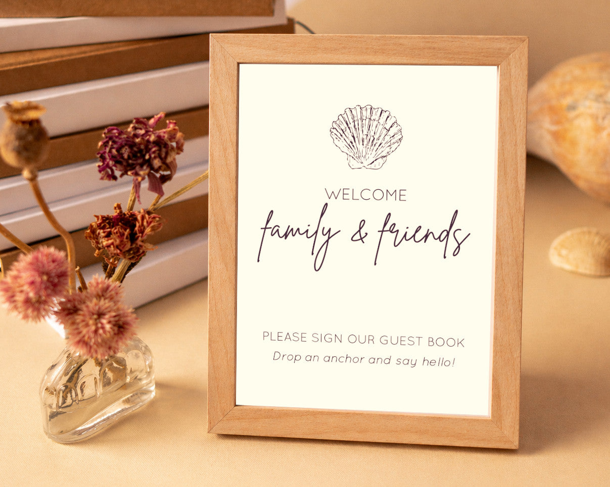 Wooden frame with a welcome sign for family and friends at a beach house on a table with decorative elements.