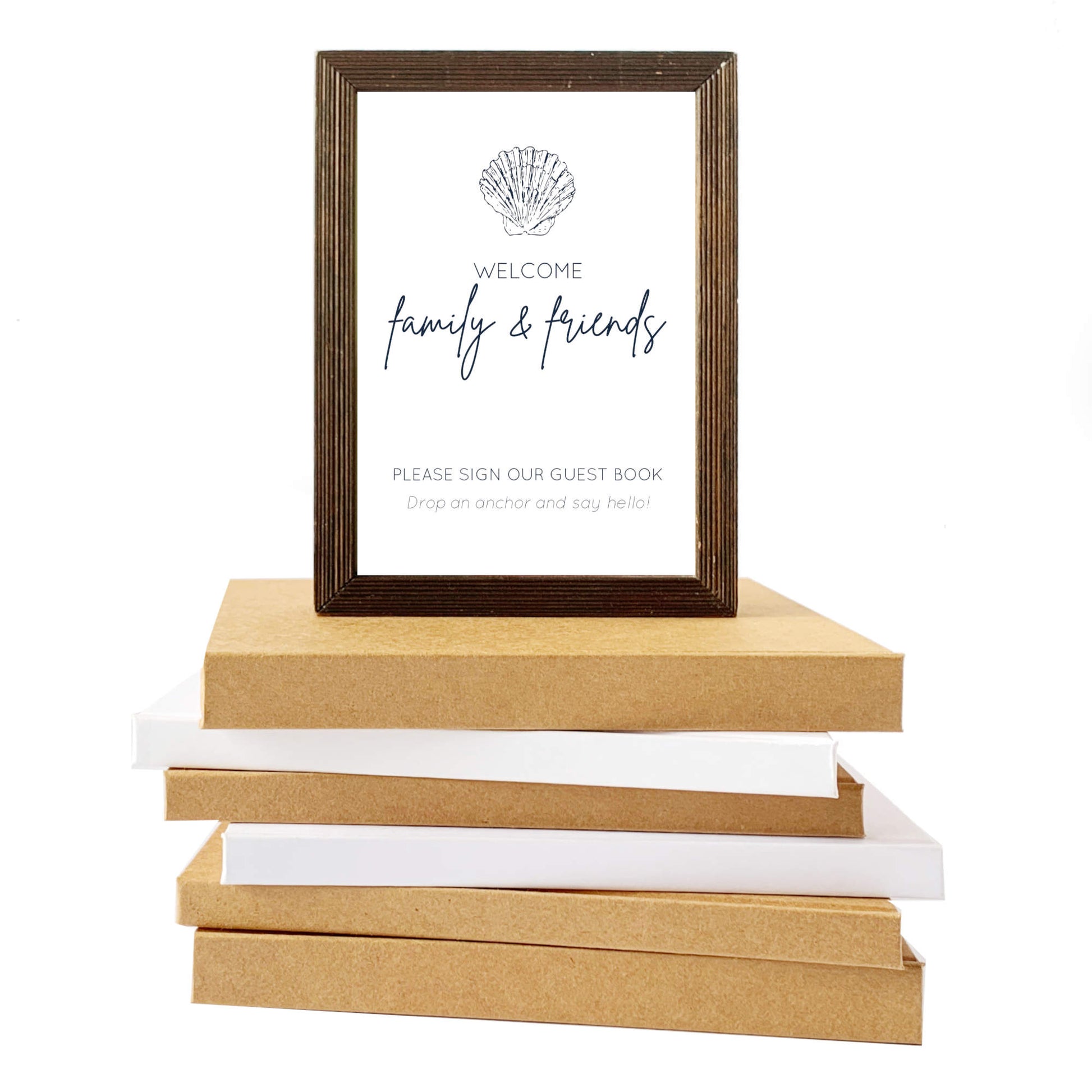 Wooden photo frame on top of a stack of books with a white background. Frame holds custom table sign for beach house guest book encouraging friends and family to leave a special message in the guest book.