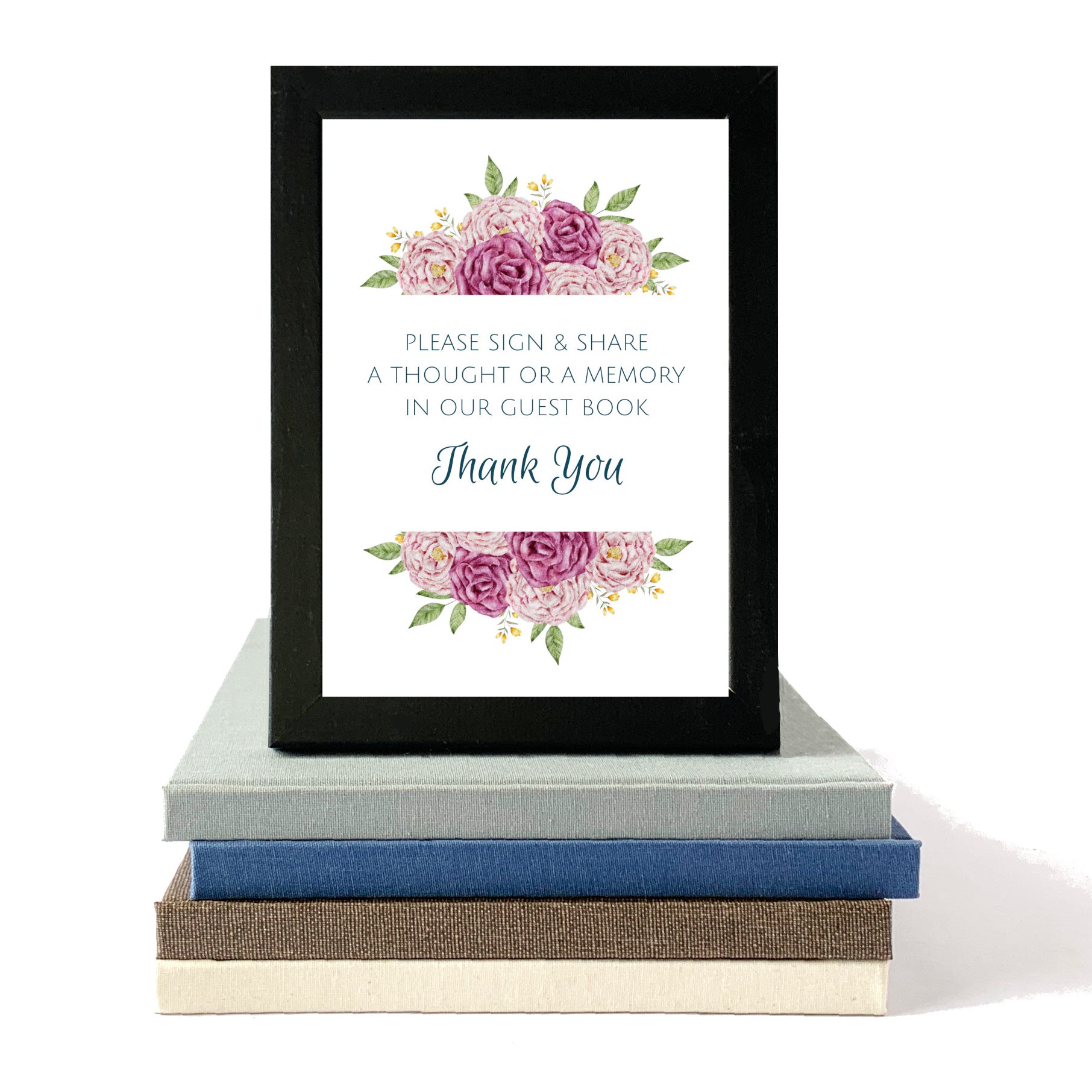 Framed guest book sign with floral design and text on a stack of books.