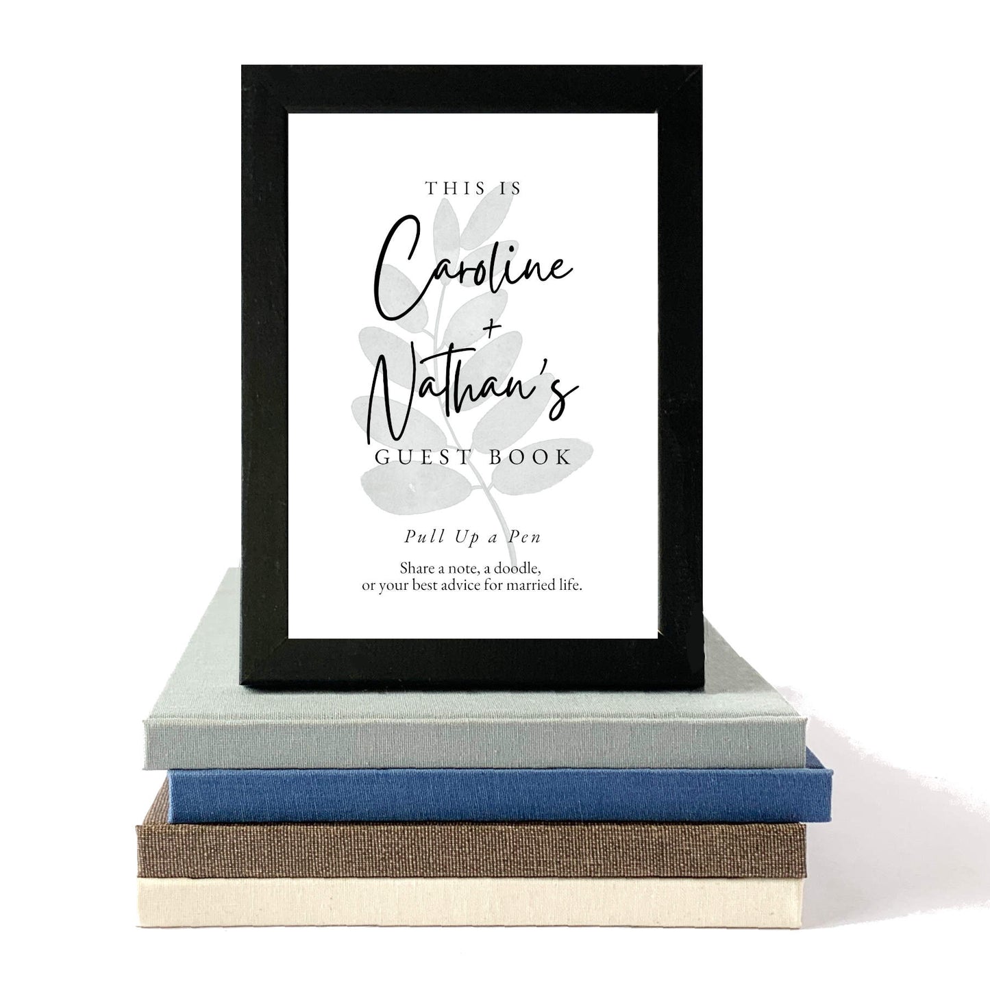 Framed guest book sign with decorative elements on a stack of books. Custom table sign for wedding guest made to match personalized hand bound book. Ready for guest book table.