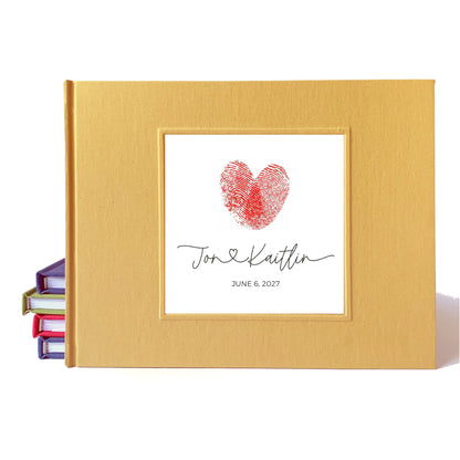 A personalized warm yellow linen wedding guest book with a white insert featuring a red heart-shaped fingerprint and the names 'Jon & Kaitlin' with the date 'June 6, 2027'.