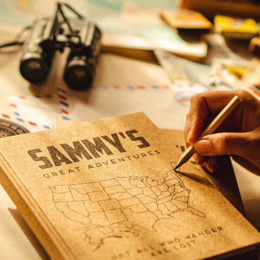 Person coloring in the map on a customized travel planning book cover, personalizing their adventure.