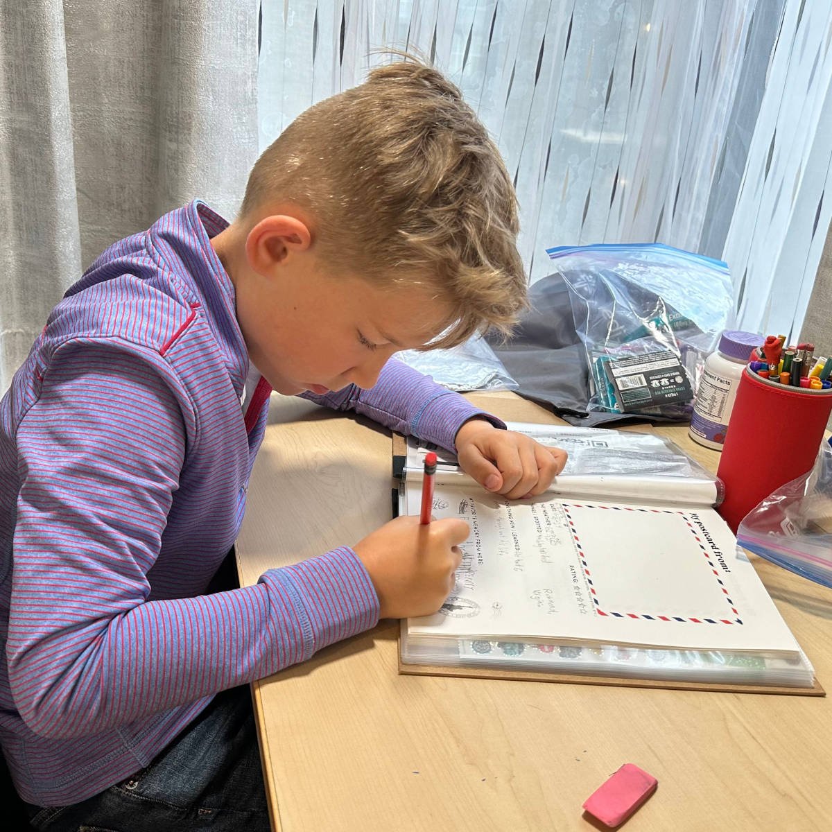 Boy using a travel scrapbook with removable pages, adding memories and personal touches to his adventure journal.