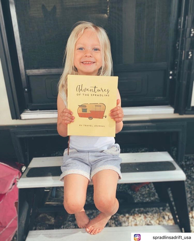 Adorable little girl holding a custom RV travel log – perfect camping essentials for families on the road.