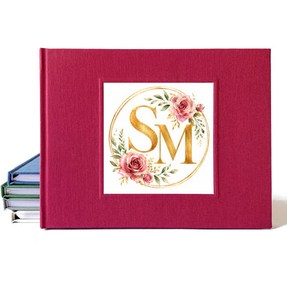 Burgundy linen wedding guest book with a rose and gold watercolor wedding crest design on the cover.