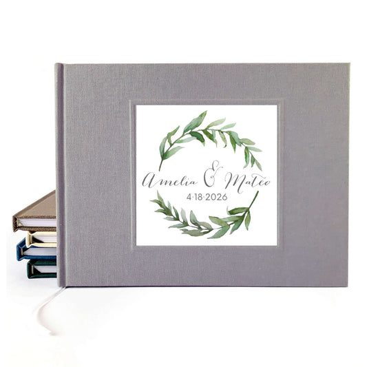 Gray linen wedding guest book with personalized watercolor wreath artwork on the cover. Hardback, hand crafted, layflat pages.