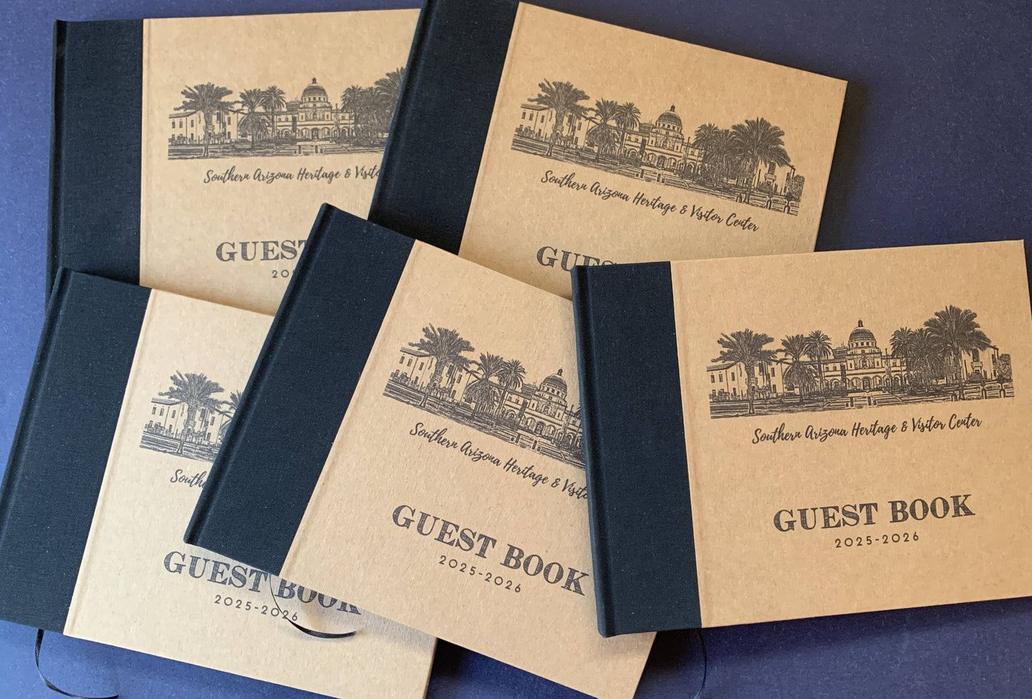 Set of personalized wholesale guest books with custom artwork and text on the covers on a blue background